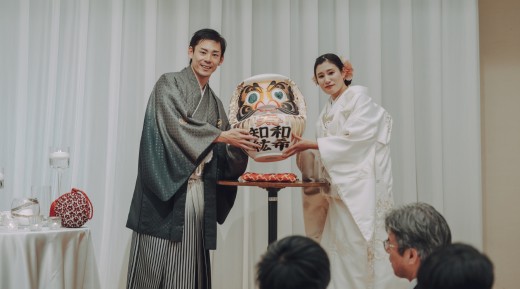 和装新郎新婦がだるまを持っている